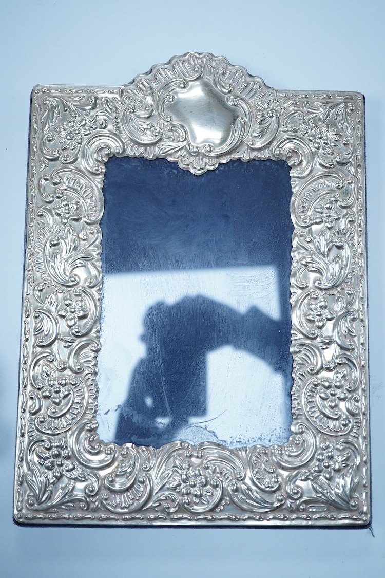 An Edwardian repousse silver mounted photograph frame, by Synyer & Beddoes, Birmingham, 1901, 23.4cm, together with a George V plain silver rectangular photograph frame, with ribbon bow crest, Stuart Clifford & Co, Londo